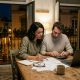 Young couple at a kitchen table in Málaga working out property purchase costs with a calculator and documents