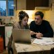 Young couple comparing household bills on a laptop at a kitchen table in a Spanish flat, butane bottle nearby