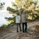 Retired couple walking a golden retriever on a pine-lined path near the sea in Nerja in the early morning