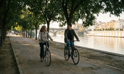 Mother and adult son cycling along the Guadalquivir riverside path in Triana, Seville, on a sunny autumn morning