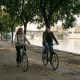 Mother and adult son cycling along the Guadalquivir riverside path in Triana, Seville, on a sunny autumn morning