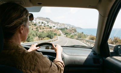 Woman driving on a sunny coastal road in Andalusia with a white village and the sea ahead