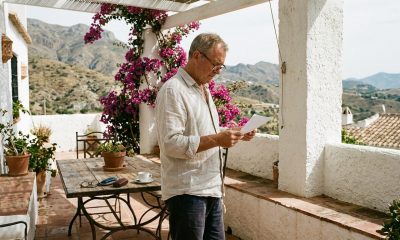 Expat homeowner reading a town hall letter on the terrace of a whitewashed Spanish villa