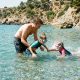 Father and two young children snorkelling in clear turquoise water below the cliffs at Maro beach near Nerja