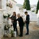 Three generations of a Spanish family placing chrysanthemums on a cemetery niche in an Andalusian village on a sunny morning
