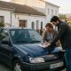 Two drivers filling in a joint accident report on a car bonnet in a quiet Spanish village street