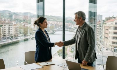 Young woman shaking hands with an older HR manager in a modern Bilbao office on her first day at work