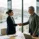 Young woman shaking hands with an older HR manager in a modern Bilbao office on her first day at work