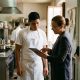 Young new employee reviewing his job paperwork on a tablet with an HR manager at a hotel kitchen in Seville
