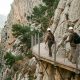 Hikers in safety helmets walking the Caminito del Rey boardwalk above the Gaitanes gorge in the morning