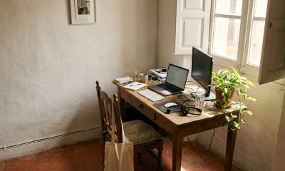 Home office corner in a Spanish apartment with a laptop, external monitor and keyboard by a window
