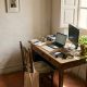 Home office corner in a Spanish apartment with a laptop, external monitor and keyboard by a window