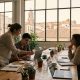 Three young professionals working together in a bright coworking space in Malaga with old town rooftops behind
