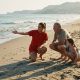 Young lifeguard talking to a grandfather and his granddaughter on the sand at a Costa del Sol beach in late afternoon light