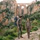 Young couple with a toddler in a carrier hiking below Ronda's Puente Nuevo at sunrise in spring