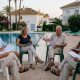 Neighbours of different ages holding an owners' community meeting beside a communal pool in a Marbella urbanisation