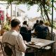 Remote worker with a laptop at a café terrace in a white Andalusian village with bougainvillea and sea view