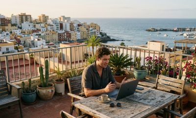 Young man working remotely on a video call from a rooftop terrace in Las Palmas with the ocean behind him