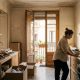 Woman in her late thirties unpacking boxes and using a laptop in a sunny new apartment in Valencia