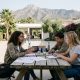 Teenage students working together at an outdoor table in a sunny school courtyard near Marbella with mountains behind