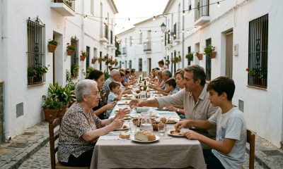 Locals and expats sharing a long table at a summer street dinner in a whitewashed Andalusian village