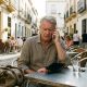 Older man on the phone at a Málaga street café with an empty wallet after losing his passport