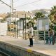 Older woman and teenage boy waiting on a sunny train platform in Benalmádena on the Costa del Sol in the morning