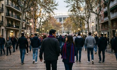 Father and teenage daughter in football scarves walking through Barcelona's Les Corts district towards the stadium at dusk
